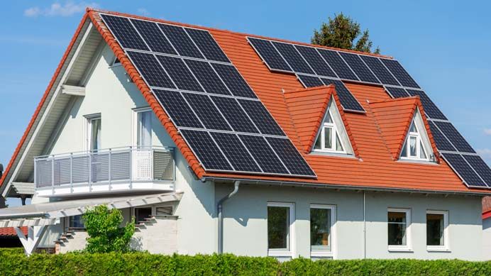 Photovoltaikmodule auf einem roten Ziegeldach mit Dachgaube
