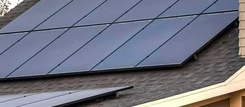 Dunkle Solarmodule neben einer Gaube auf einem Hausdach
