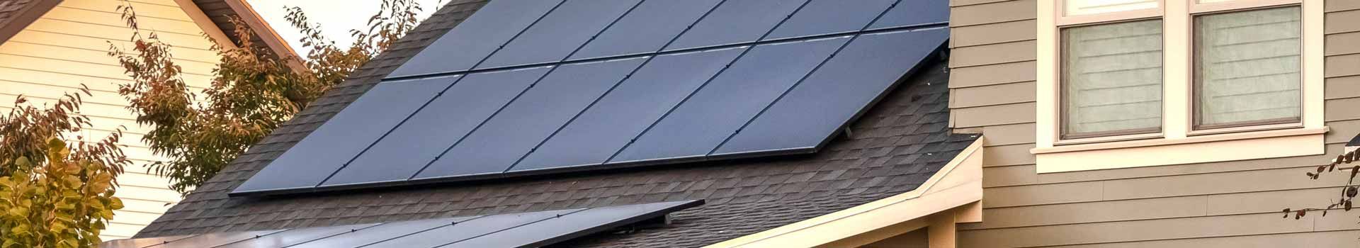 Dunkle Solarmodule neben einer Gaube auf einem Hausdach