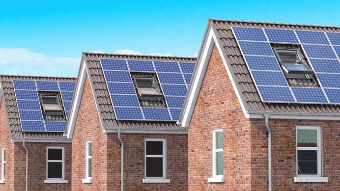 Mehrere benachbarte Hausdächer mit Photovoltaikmodulen und Dachfenstern