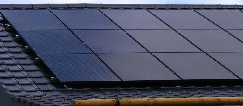 Schwarze Solarmodule auf einem dunkel gedeckten Hausdach