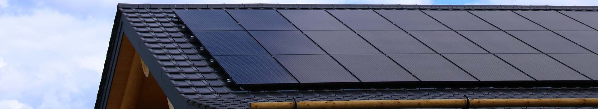 Schwarze Solarmodule auf einem dunkel gedeckten Hausdach