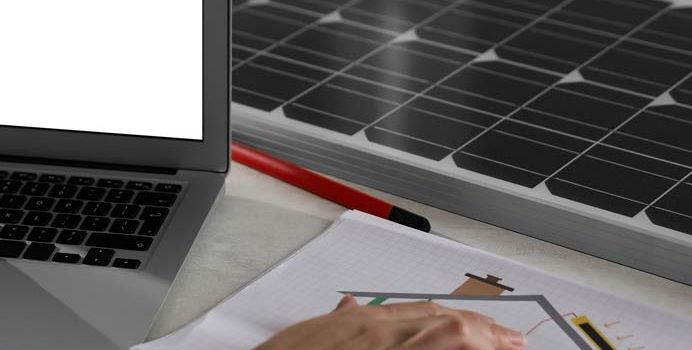 Planungsunterlagen, Laptop und Solarmodul auf einem Schreibtisch