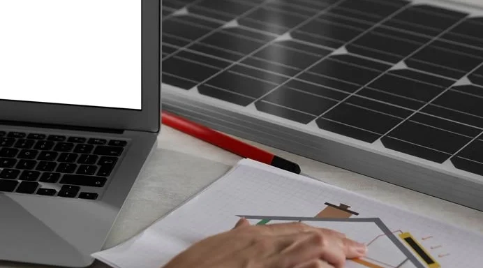 Planungsunterlagen, Laptop und Solarmodul auf einem Schreibtisch