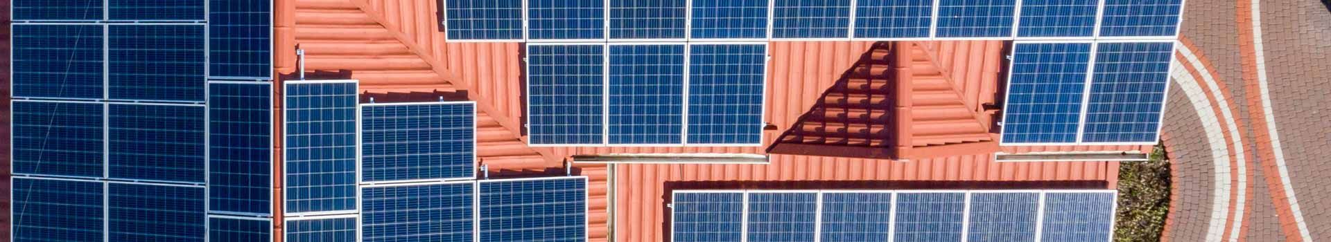 Draufsicht auf Solarmodule auf mehreren roten Dachflächen