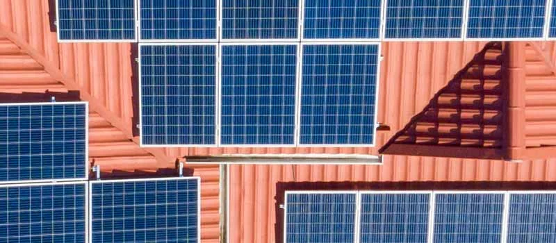 Draufsicht auf Solarmodule auf mehreren roten Dachflächen