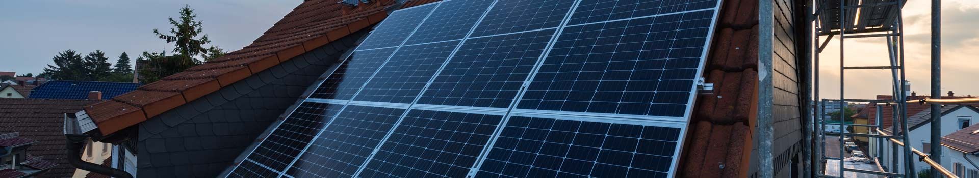 Solarmodule auf einem geneigten Dach neben einem Baugerüst