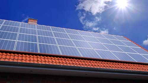 Solarmodule auf einem roten Ziegeldach bei Sonnenschein