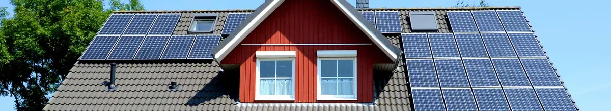 Solarmodule auf einem Hausdach rund um eine Gaube und Dachfenster