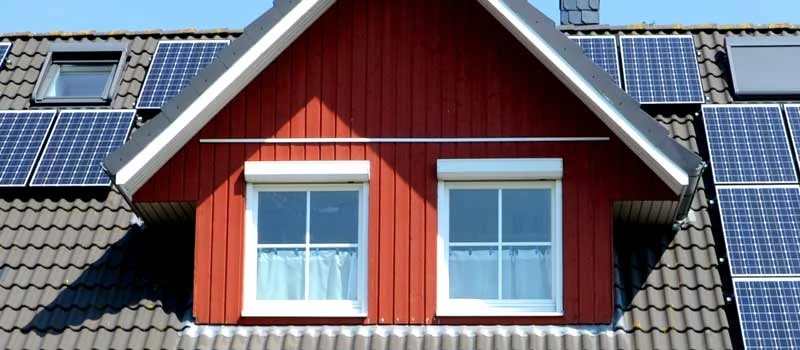 Solarmodule auf einem Hausdach rund um eine Gaube und Dachfenster