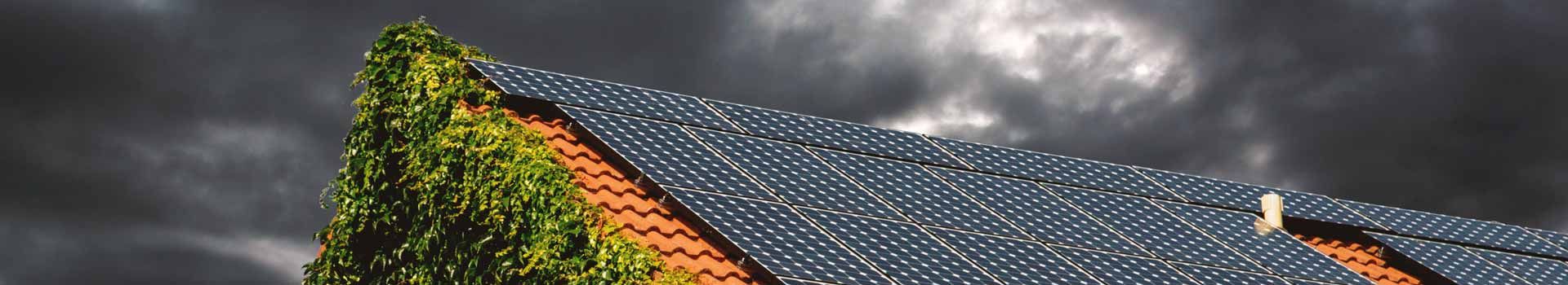 Solarmodule auf einem Ziegeldach unter dunklen Wolken