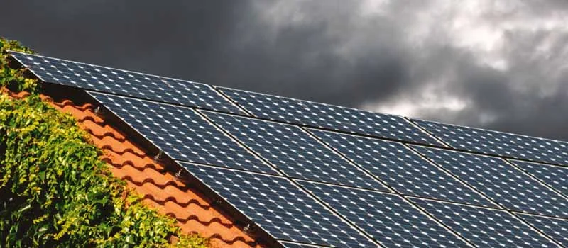 Solarmodule auf einem Ziegeldach unter dunklen Wolken