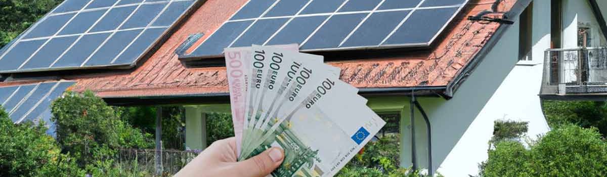 Symbolbild zu PV-Kosten: Geldscheine vor einem Haus mit Solarmodulen