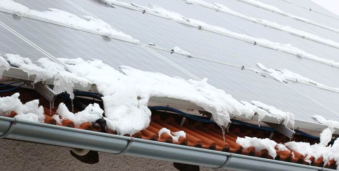 Solarmodule auf einem Ziegeldach mit Schnee an den Modulrändern