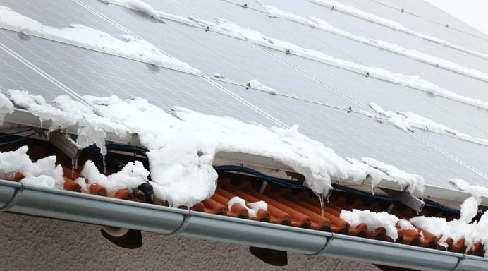 Solarmodule auf einem Ziegeldach mit Schnee an den Modulrändern
