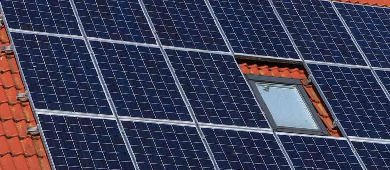 Solarmodule zwischen Dachfenstern auf einem roten Ziegeldach