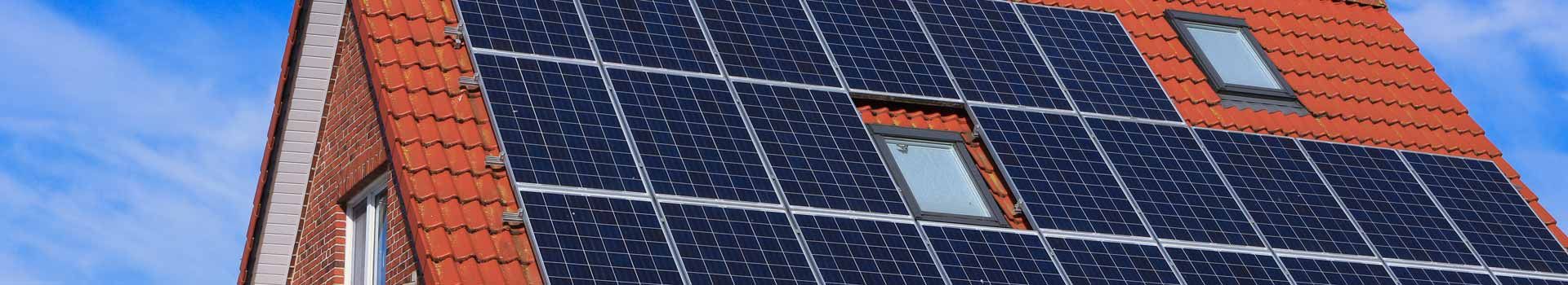 Solarmodule zwischen Dachfenstern auf einem roten Ziegeldach