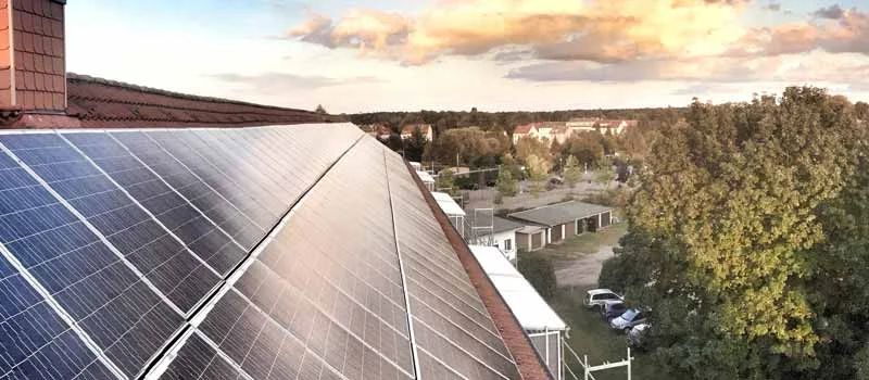 Solarmodule neben einem Schornstein auf einem roten Ziegeldach
