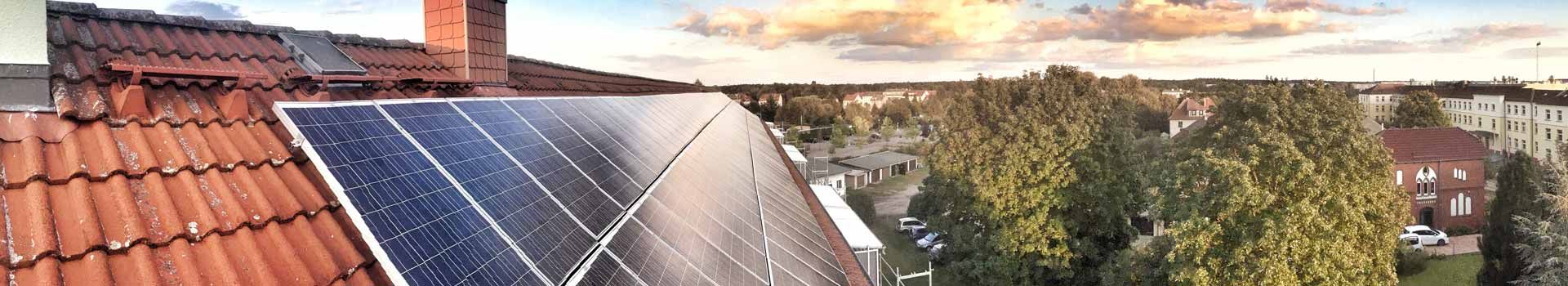 Solarmodule neben einem Schornstein auf einem roten Ziegeldach