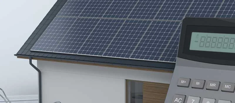 Symbolbild zur Wirtschaftlichkeit: Haus mit Solarmodulen und Taschenrechner