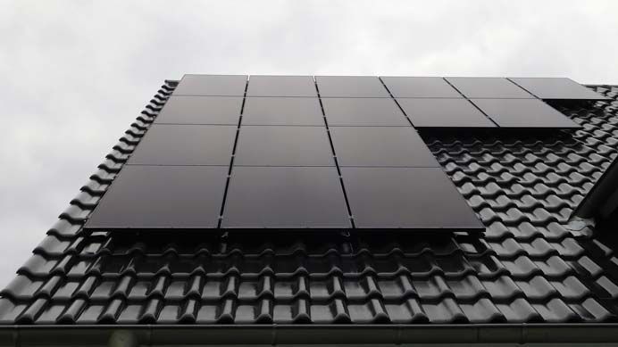 Schwarze Solarmodule auf einem dunkel gedeckten Hausdach